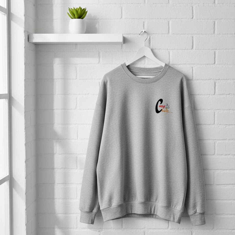 Gray sweatshirt with a logo on a hanger against a white brick wall.